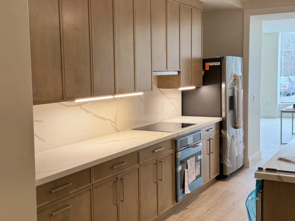 A completed custom kitchen cabinet installation featuring natural wood grain finishes and under-cabinet LED lighting elements.