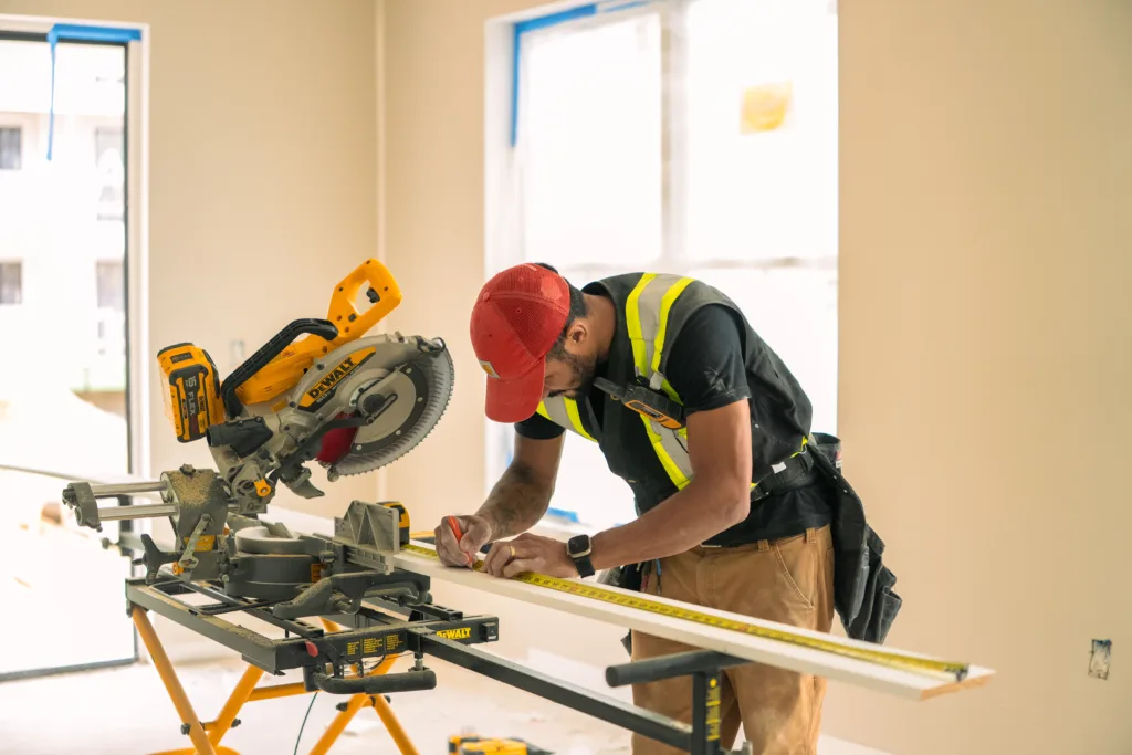 Carpenter measuring and cutting baseboards on a miter saw for the Townhouse Interior Trim.